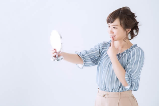 鏡で歯を見る女性